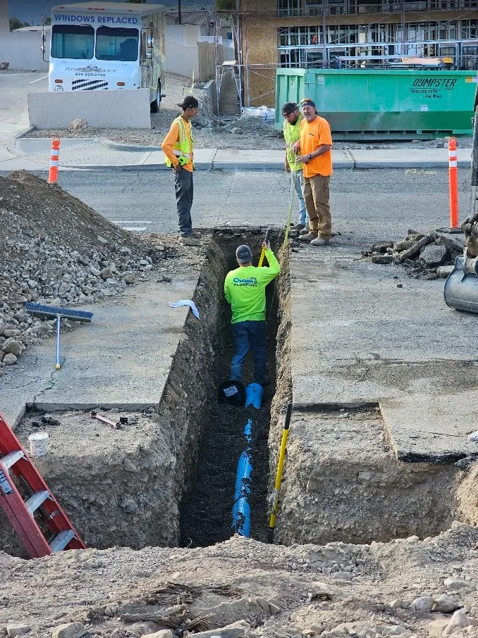 Craig Plumbing crew laying new pipe in an open trench at a commercial job site