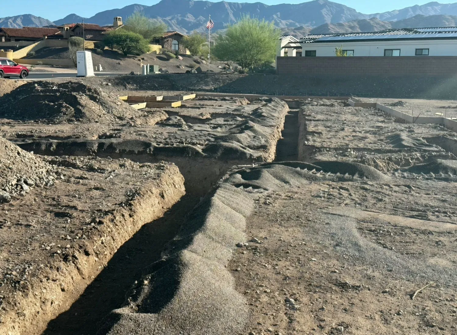 Plumbing trenches dug across a new home site on a desert hillside